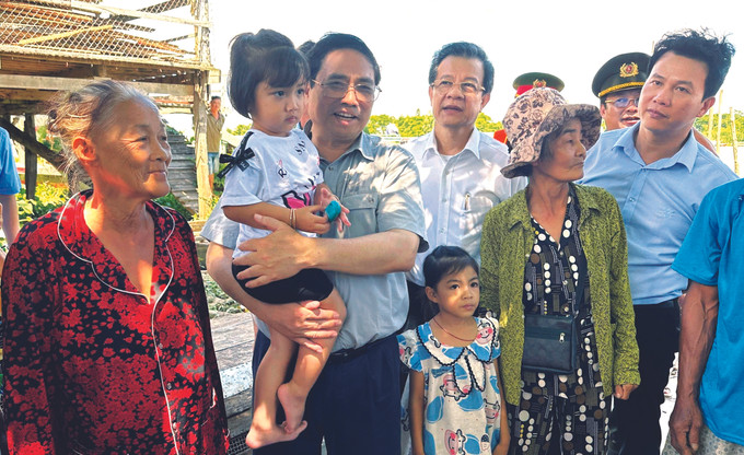 នាថ្ងៃទី ១២ ខែ សីហា ឆ្នាំ ២០២៣ នាយករដ្ឋមន្ត្រីនៃរដ្ឋាភិបាល ផាម មិញជិញ រួមជាមួយតំណាងបណ្តាក្រសួង ស្ថាប័ននិងថ្នាក់ដឹកនាំបណ្តាមូលដ្ឋានចុះធ្វើអធិការកិច្ចស្ថានការណ៍បាក់ដីមាត់សមុទ្រនៅបណ្តាខេត្ត កាម៉ៅ កៀនយ៉ាង និង ដុងថាប។ ក្នុងរូបថត៖ នាយករដ្ឋមន្ត្រីនៃរដ្ឋាភិបាល ផាម មិញជិញ អញ្ជើញសួរសុខទុក្ខប្រជាជនស្នាក់នៅតំបន់ឆ្នេរសមុទ្រនៃខេត្ត កៀនយ៉ាង សកម្មភាពមួយចំនួនរបស់ថ្នាក់ដឹកនាំបក្សនិងរដ្ឋ ảnh 2