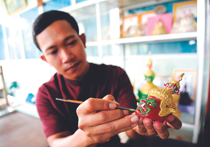 ថាច់ហ្វ៊ិញធឿន បានសិក្សាស្រាវជ្រាវ ច្នៃបង្កើតថ្មីទម្រង់រូបភាពមកុដ របាំងមុខបង្រួមតូចជាច្រើនប្រភេទក្នុងគោលបំណងធ្វើអោយផលិតផលហត្ថកម្មវិចិត្រសិល្បៈប្រពៃណីរបស់ជនជាតិ ខ្មែរ ណាមបូ កាន់តែសម្បូរបែបថែមទៀត សិប្បករវ័យក្មេងម្នាក់ ជាមួយនឹងក្ដីប្រាថ្នាចង់អភិរក្សវប្បធម៌ ខ្មែរ ảnh 2