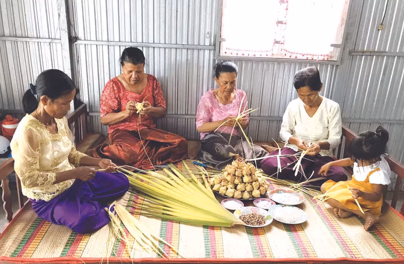 អ្នកស្រី នាង ភឿង (ទីពីរ ពីស្តាំទៅឆ្វេង) ណែនាំអ្នកម្តាយទាំងឡាយ បងៗ ស្រីនៅឃុំ អូឡឹម ស្រុក ទ្រីតូន (ខេត្ត អានយ៉ាង) ពីរបៀបវេចនំក៏ដូចជារបៀបលាយគ្រឿងផ្សំត្រៀមរៀបចំវេចនំ កាតំ
