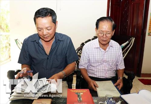 វរសេនីយ៍ឯក ហាស៊ន់ថាញ់ (ខាងស្តាំ) និង វរសេនីយ៍ទោ ធៀវក្វាងថាច់ បើកមើលទំព័រ ប្រវត្ដិសាស្ដ្រអំពីសម័យកាលចូលរួមកងទ័ពស្ម័គ្រចិត្ត ជួយប្រទេសកម្ពុជានៅលើសមរភូមិ ៧៧៩។រូបថត៖ ទីភ្នាក់ងារព័ត៌មានវៀតណាម