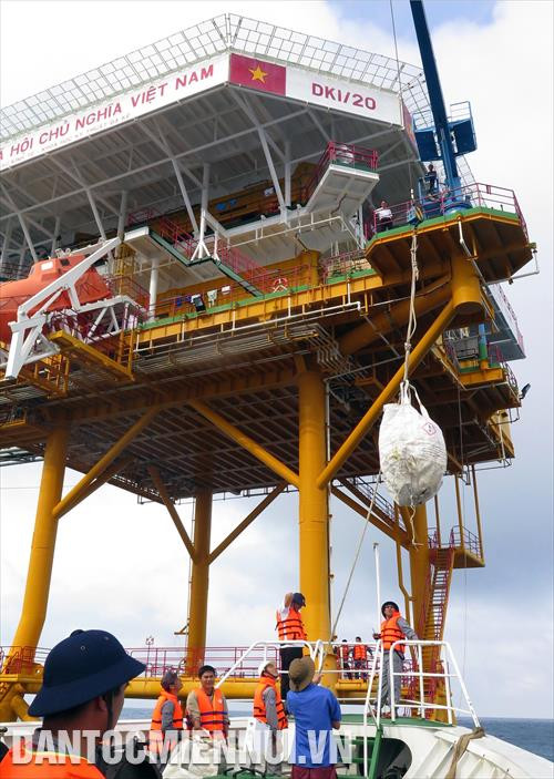 បញ្ជូនវត្ថុអំណោយបុណ្យចូលឆ្នាំថ្មីពីនាវារបស់ក្រុមការងារឡើងទៅលើផ្ទះសង់លើជើងទម្ររន្ទាខ្ពស់ផុតពីផ្ទៃទឹកសមុទ្រ។ រូបថត៖ ញូយ៉ាង