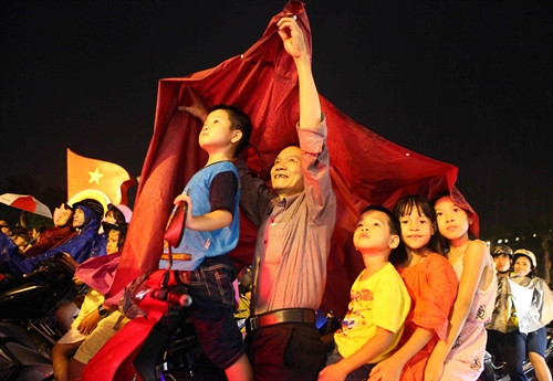 ទោះបីជាអាកាសធាតុមិនអំណោយផល ប៉ុន្តែប្រជាជនជាច្រើននៅតែទ្រាំទ្រក្រោមមេឃភ្លៀង មើលកាបាញ់កាំជ្រួចនៅបឹង ហ៊ាន់គៀម រដ្ឋធានី ហាណូយ។ រូបថត៖ ទីភ្នាក់ងារព័ត៌មានវៀតណាម