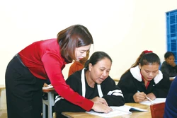 គ្រូបង្រៀនណែនាំសិក្ខាកាមក្នុងថ្នាក់រៀនលុបបំបាត់អនក្ខរកម្មនៅឃុំគីមភូ ខេត្តក្វាងទ្រី ហាត់អាន ហាត់ប្រកបអក្សរ។