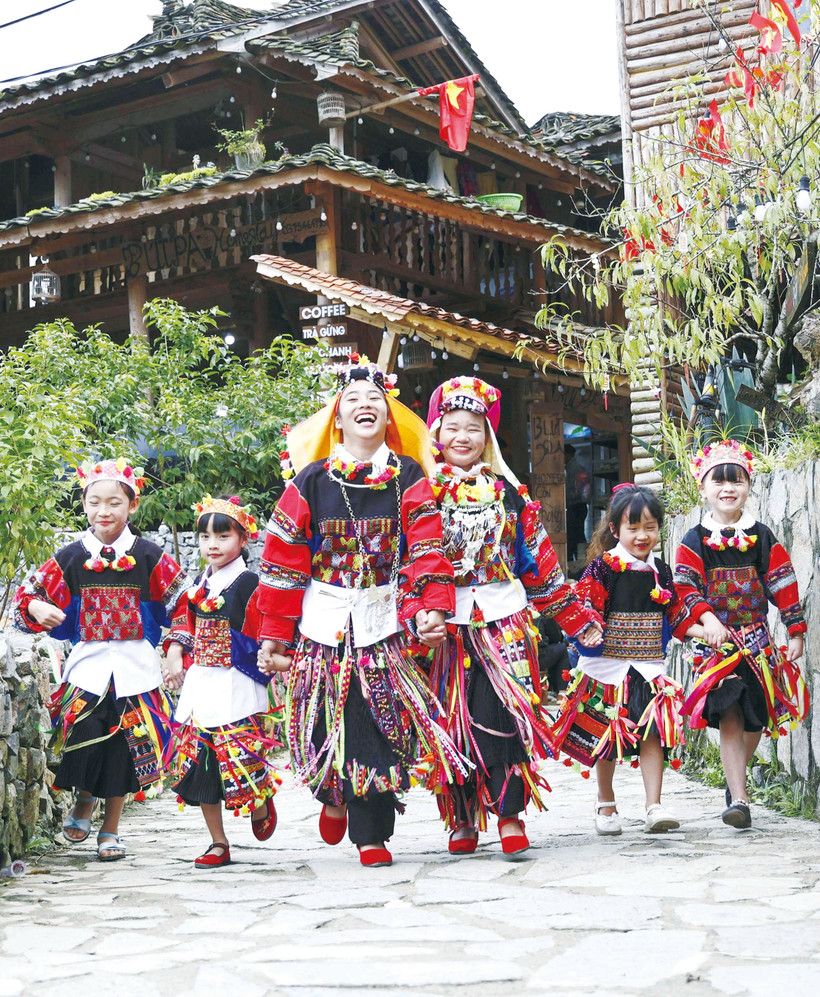 កុមារជនជាតិ ឡូឡូ ក្នុងឈុតសម្លៀកបំពាក់ប្រពៃណីនៅជើងបង្គោលទង់ជាតិ លុងគូ